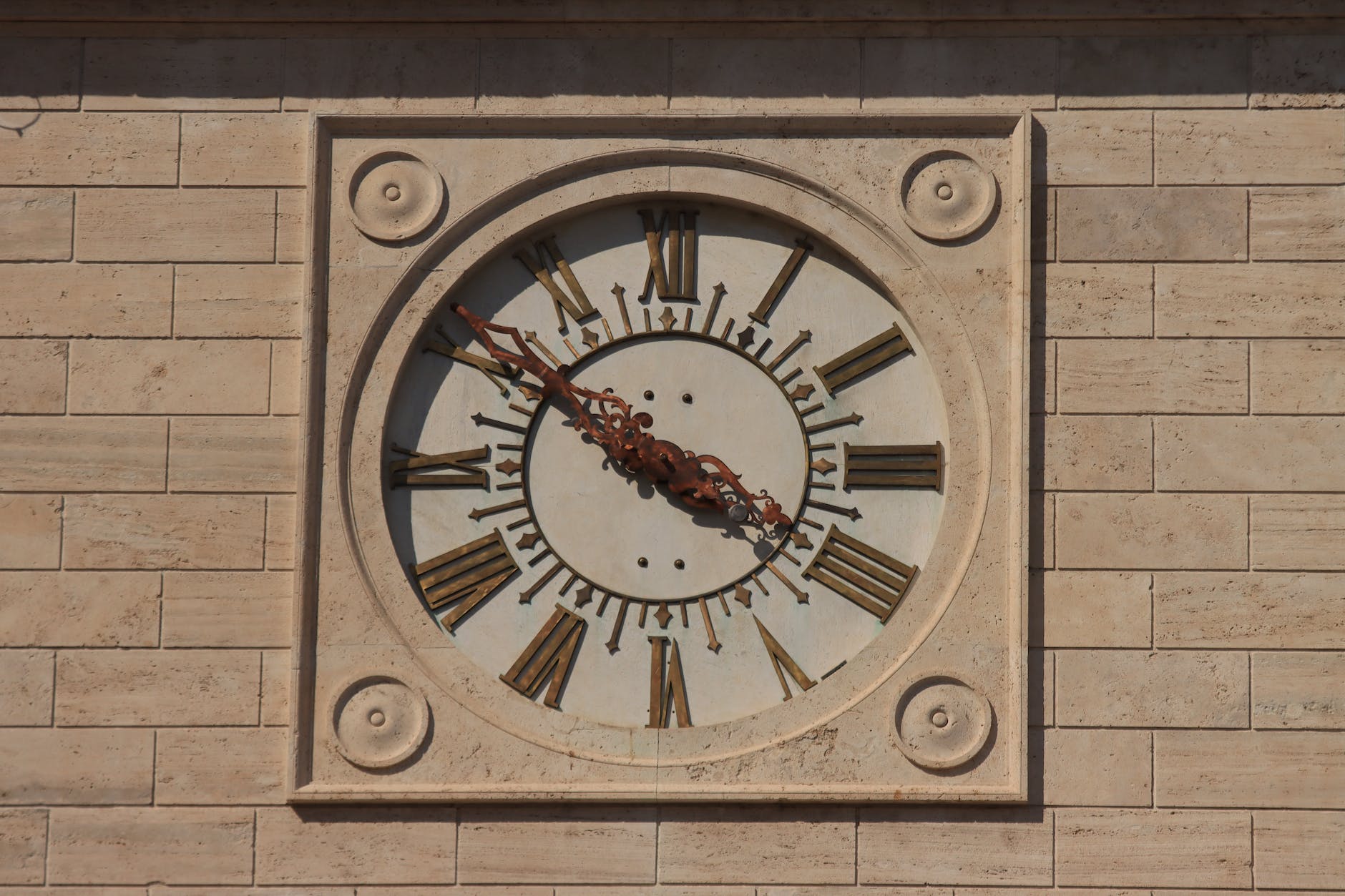 clock with latin numerals in a beige wall